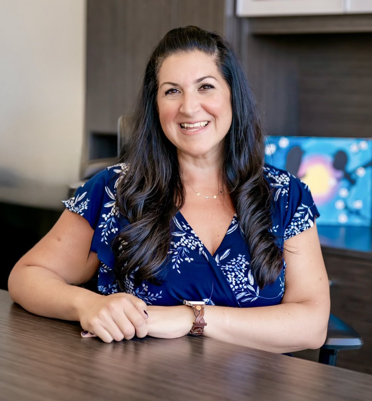 Staff member smiling at desk in blue floral top