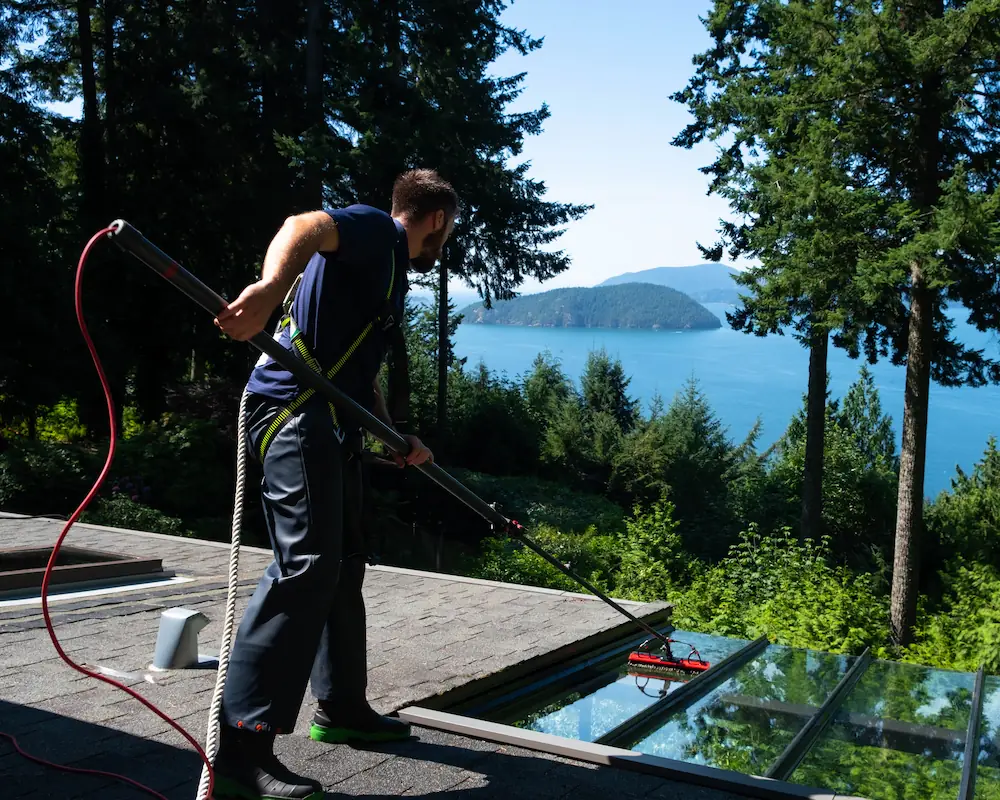 Technician cleaning exterior glass awning on residential property using extension pole system.
