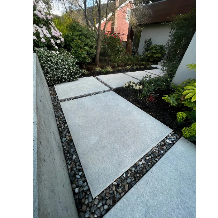 Freshly cleaned stone walkway after professional power washing in Vancouver, surrounded by landscaped plants and garden beds.