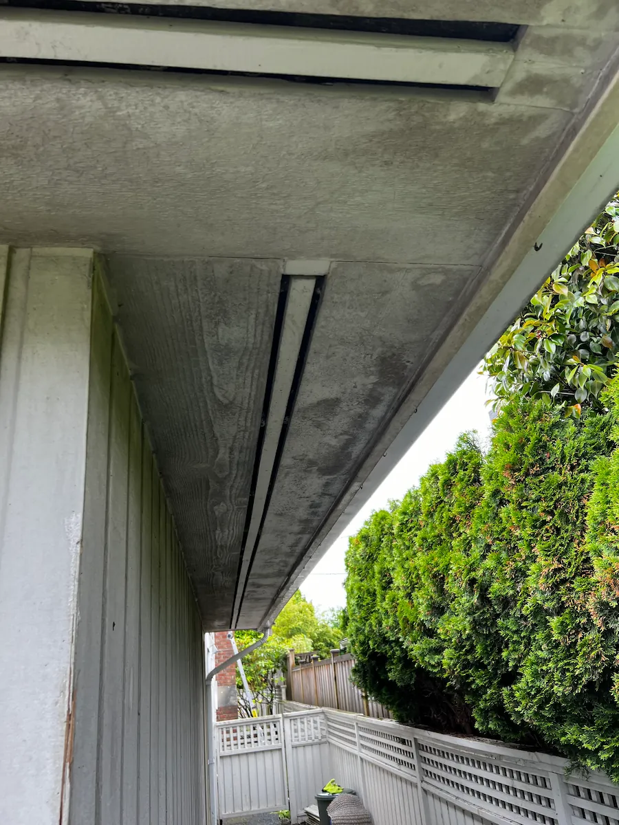 Exterior soffit and siding before soft washing, showing heavy dirt, mildew, and organic staining buildup along the roofline of a Vancouver home.