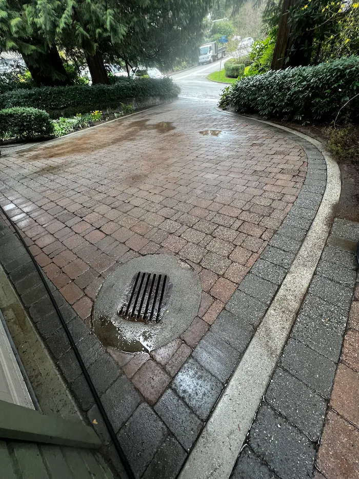 Brick driveway after pressure washing, with oil stains removed and pavers restored to a clean, uniform surface.