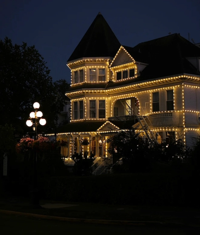 Victorian-style home in Vancouver decorated with professionally installed Christmas lights, highlighting rooflines, windows, and architectural details at night.