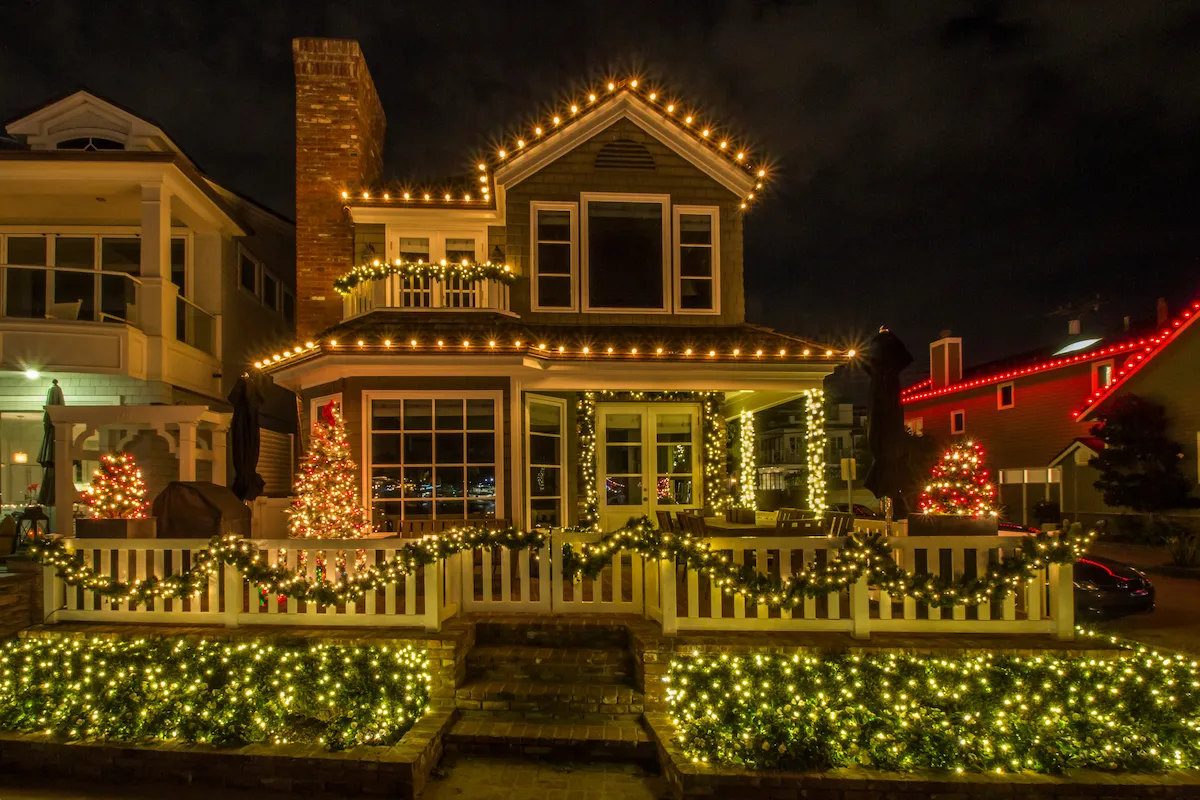 A two story house exterior illuminated by many different holiday lighting features.