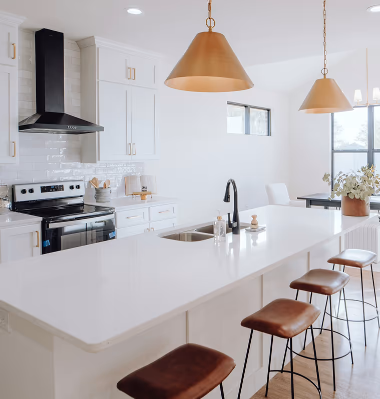 Modern white kitchen with large island, stove with range and breakfast bar.