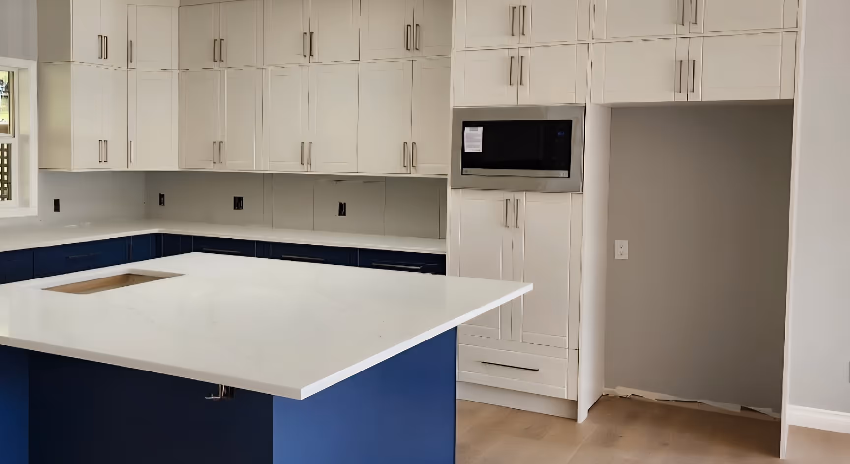 A large kitchen with white upper cabinets and blue lower cabinets.