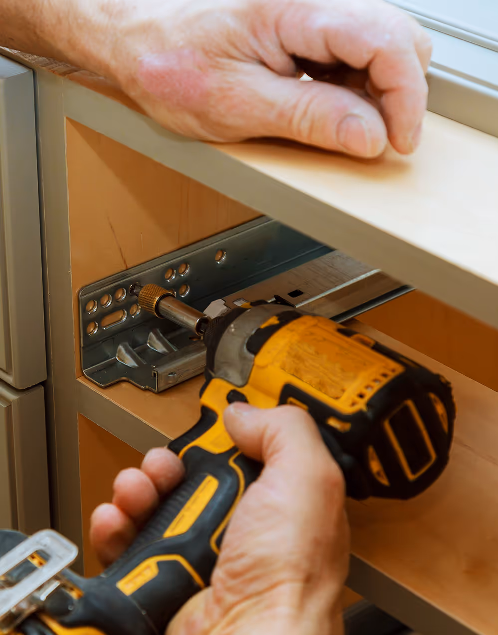 hands screwing in the guides that will hold a cabinet