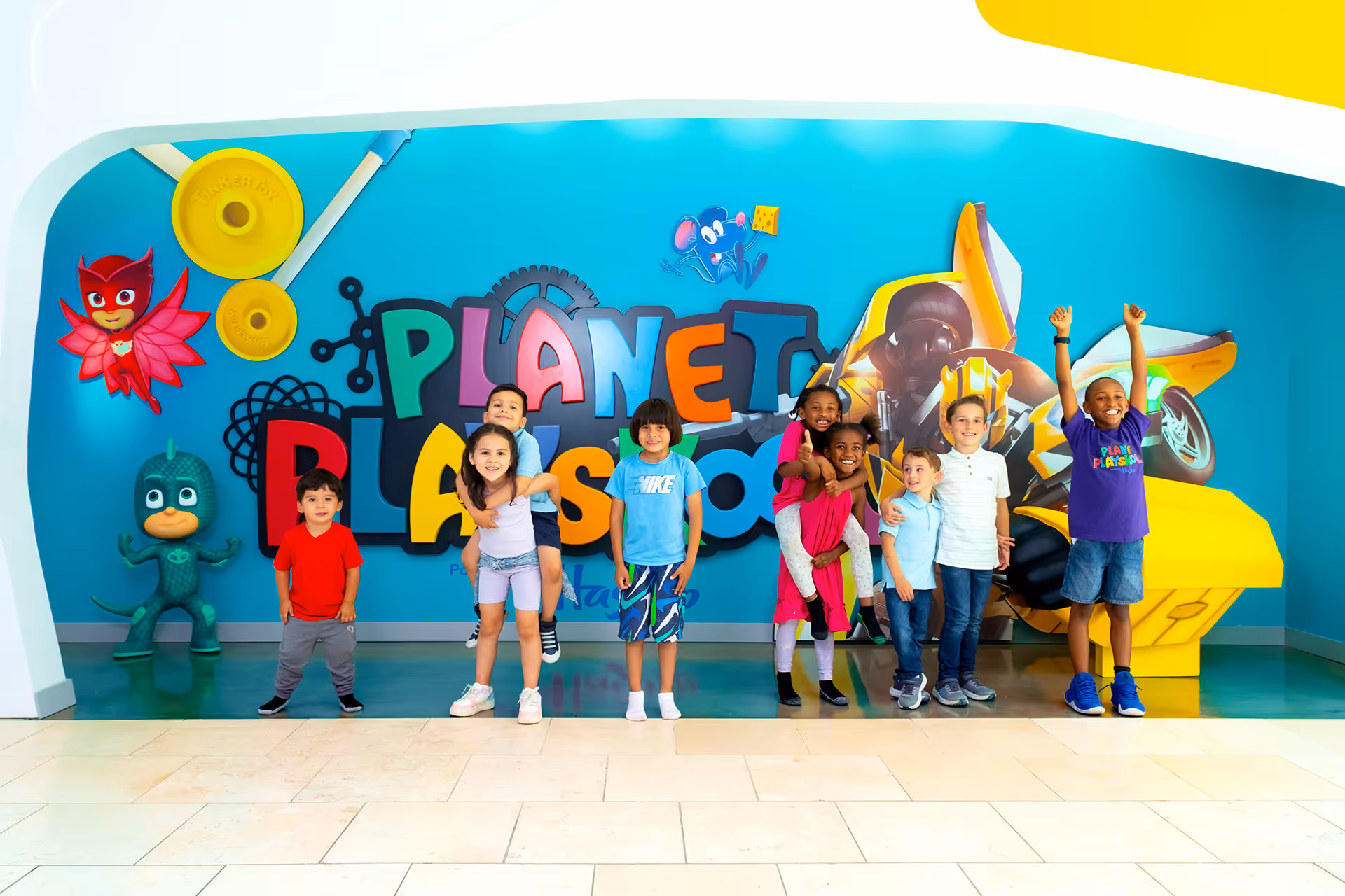A group of kids posing in front of Planet Playskool.