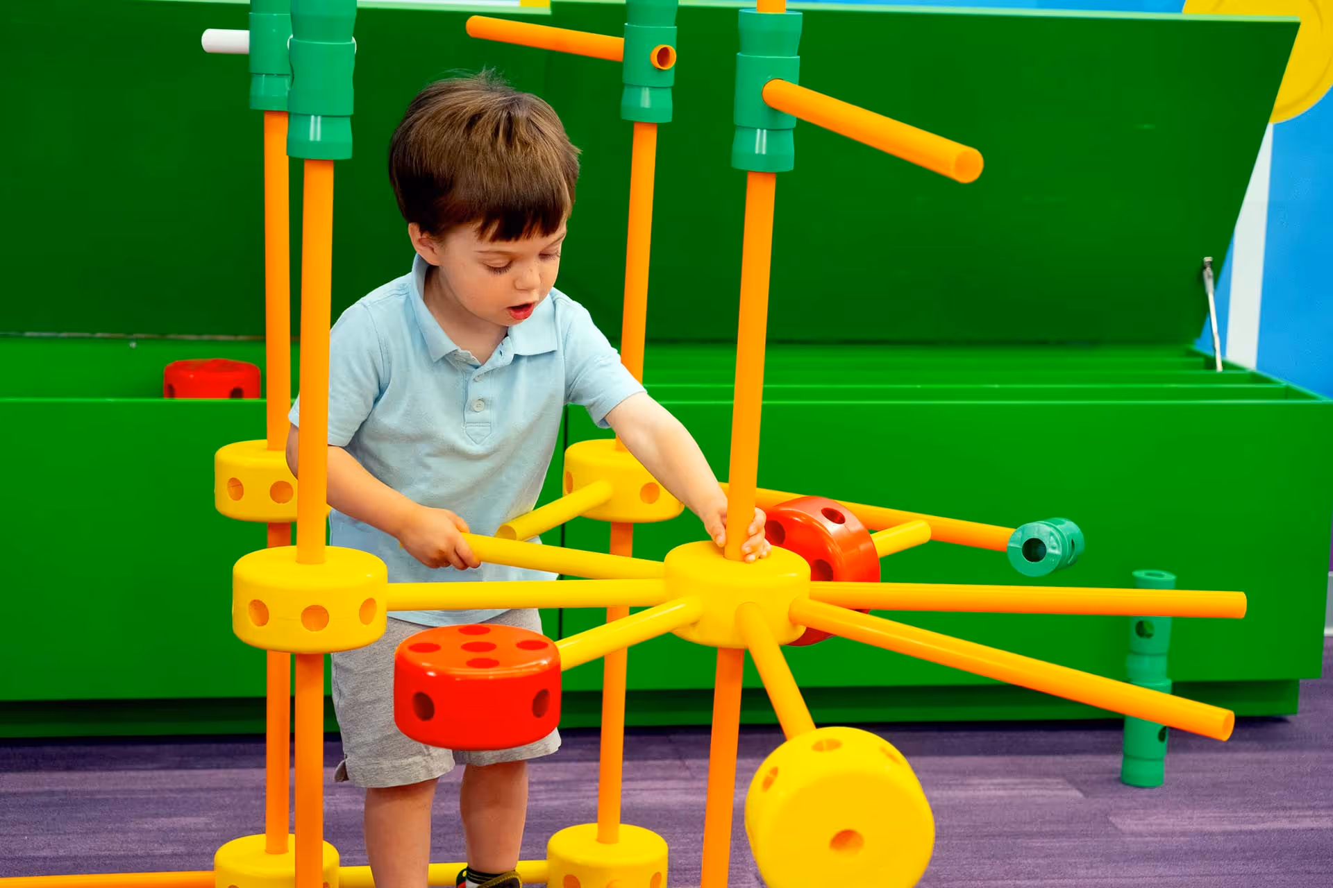 A little boy playing with snap-together toys at the TinkerToy Town area in Planet Playskool.