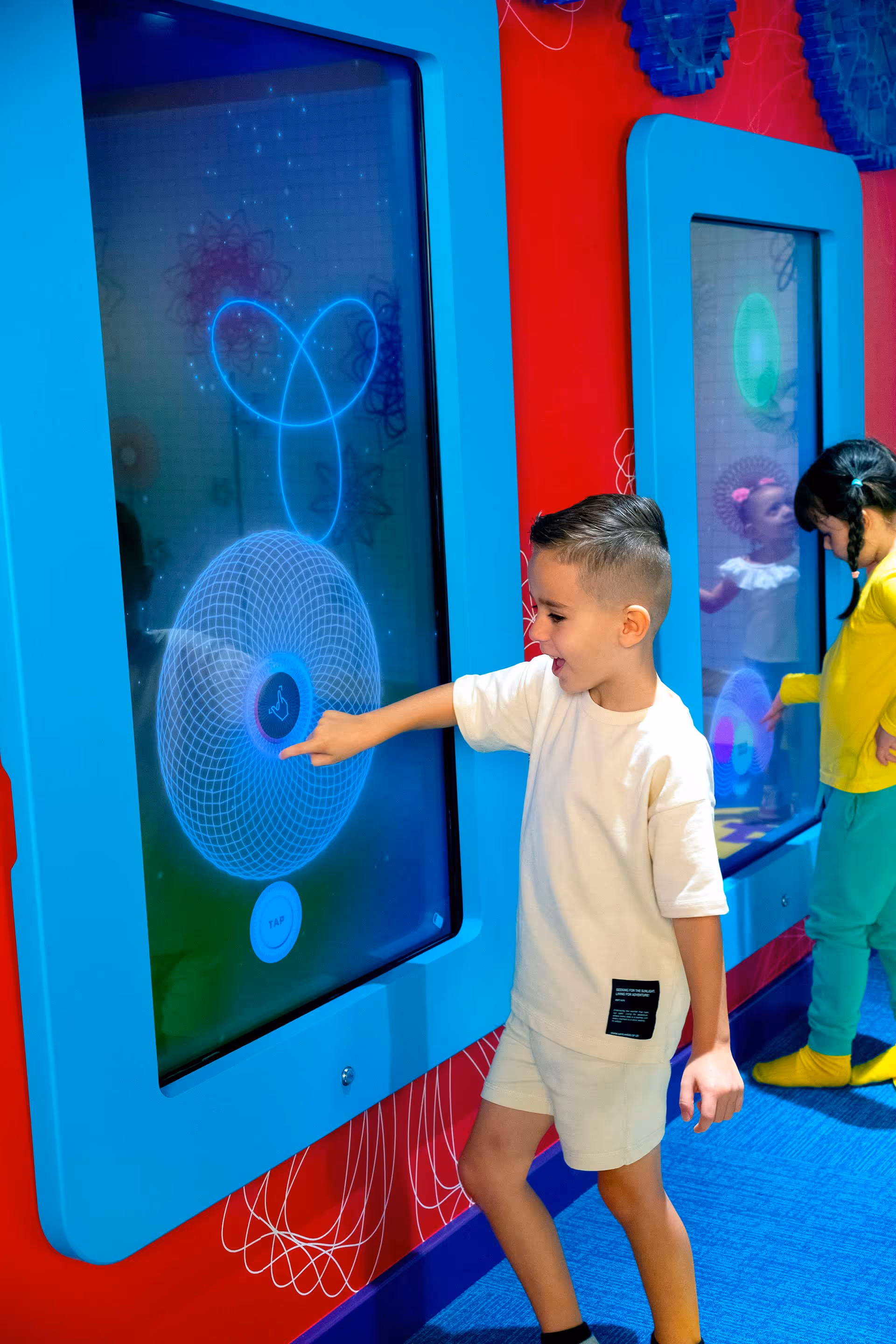Little boy interacting with a touch screen in the Spirograph Art Studio area in Planet Playskool.