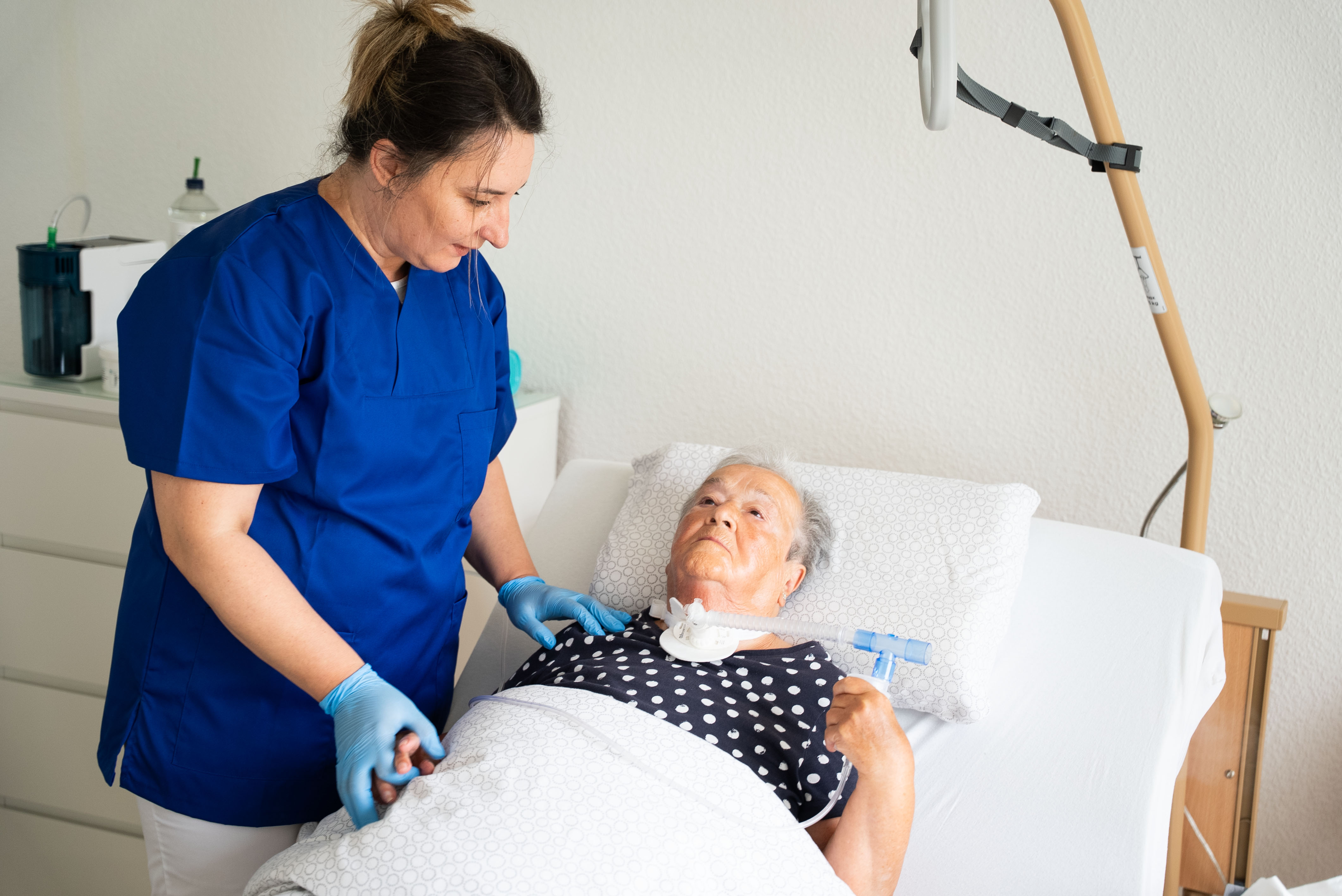 Pflegefachkraft betreut eine Patientin mit Trachealkanüle nach der Entlassung aus dem Krankenhaus