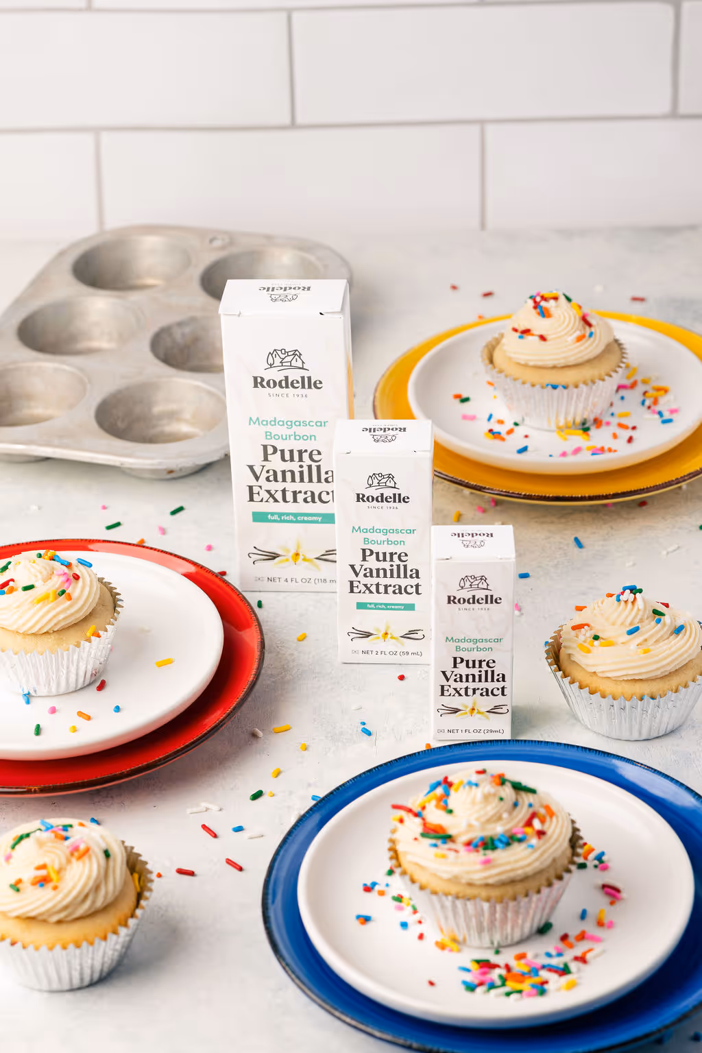 A picture of vanillas from Colorado based CPG brand Rodelle next to 3 cup cakes on a counter.