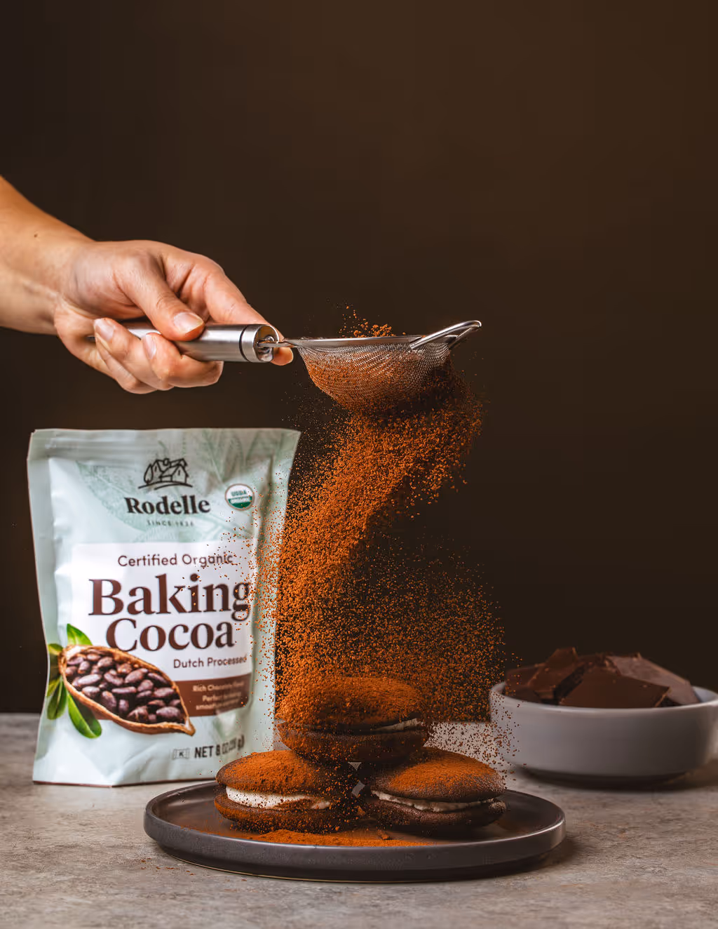 A picture of coca powder from Colorado based CPG brand Rodelle being poured over some cream pies