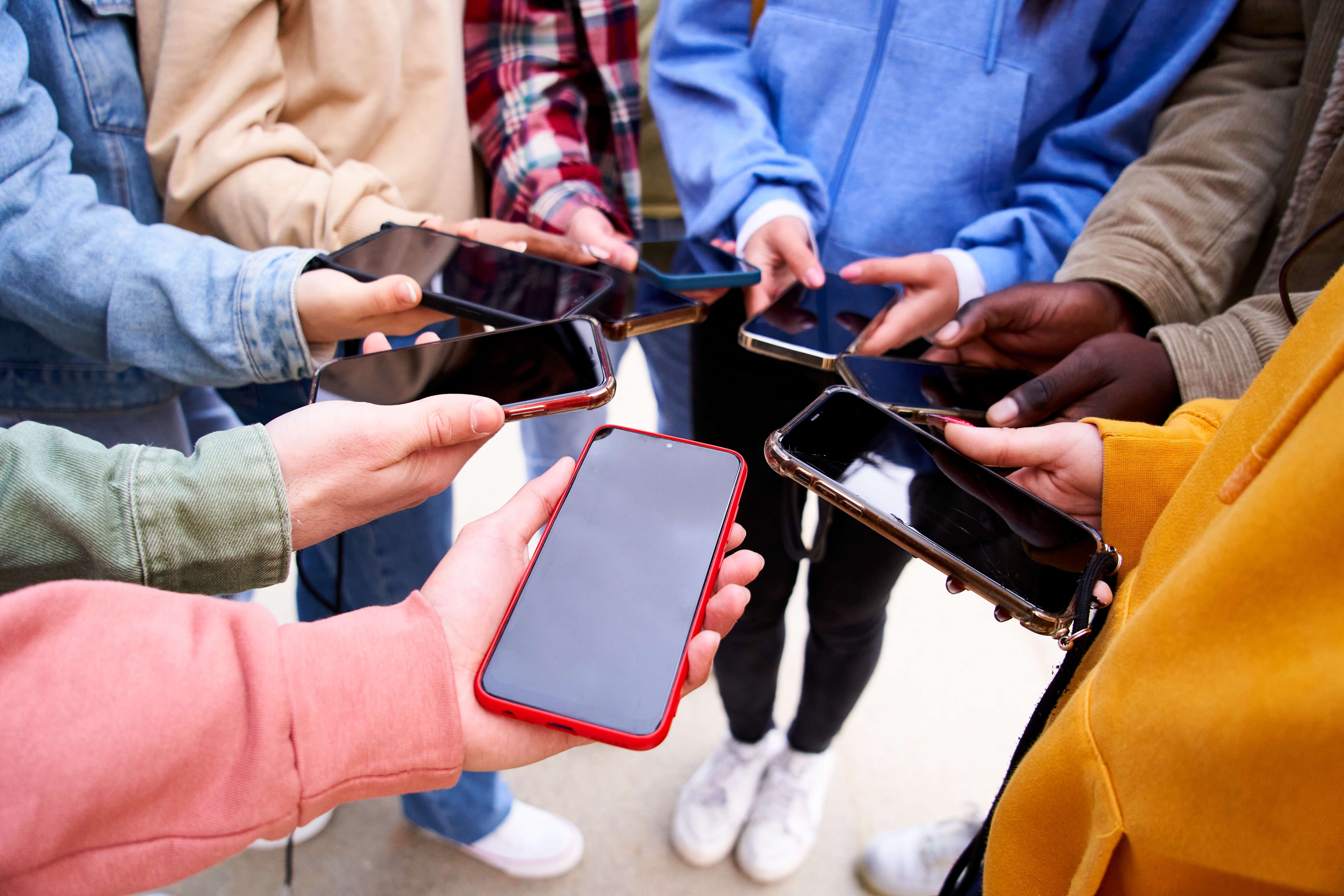Eight people standing in a circle holding their phones together.