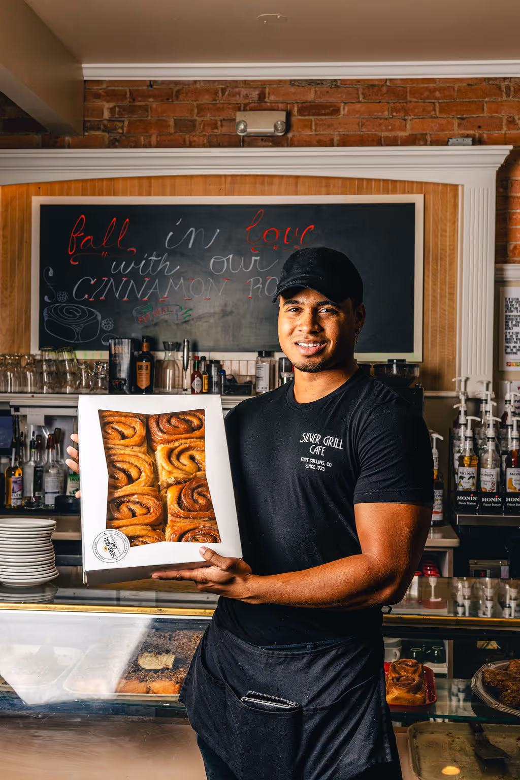 A man holding a box of cinnamon rolls at the Colorado restaurant the Silver Grill