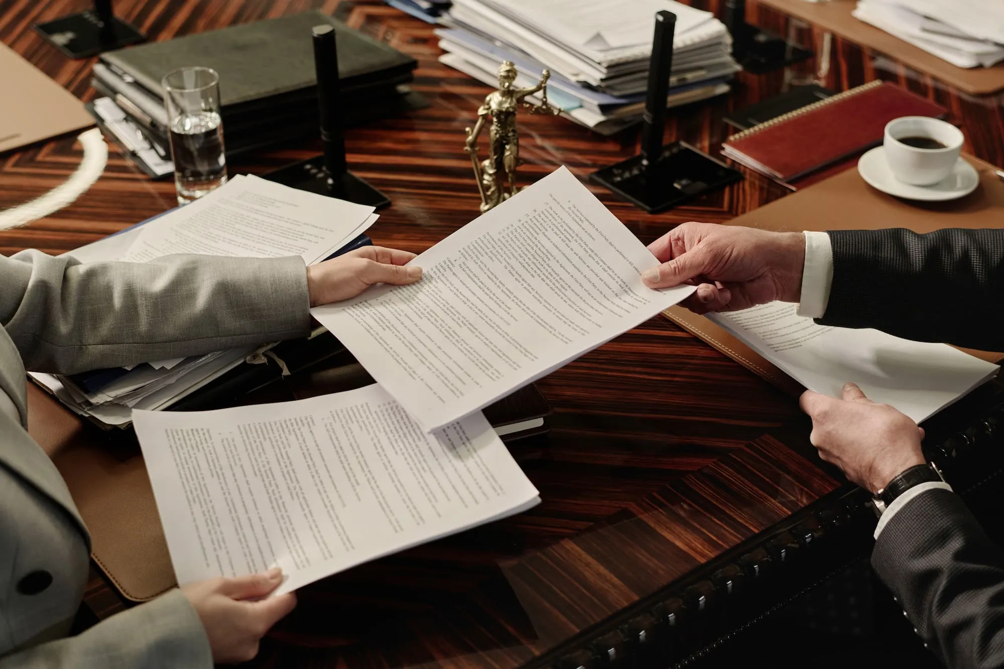 two attorneys exchanging documents sitting side by side