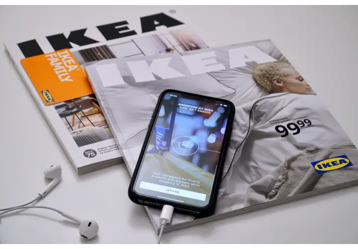 Two IKEA catalogs lying on a table with a mobile n top showing the IKEA catalog