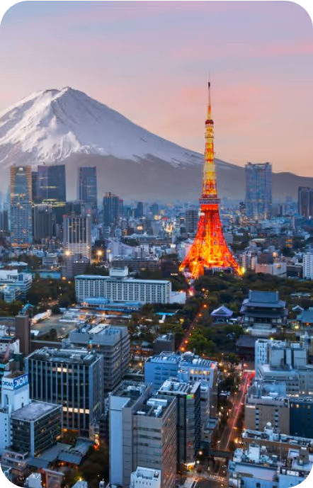 Cityscape of Tokyo with Tokyo Tower illuminated and Mount Fuji in the background at sunset.
