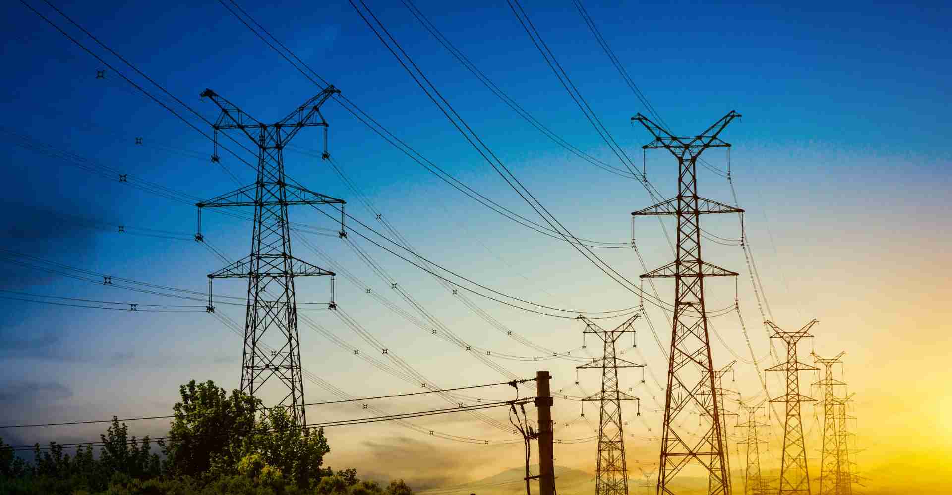 Electrical transmission towers beneath a blue and gold sunset