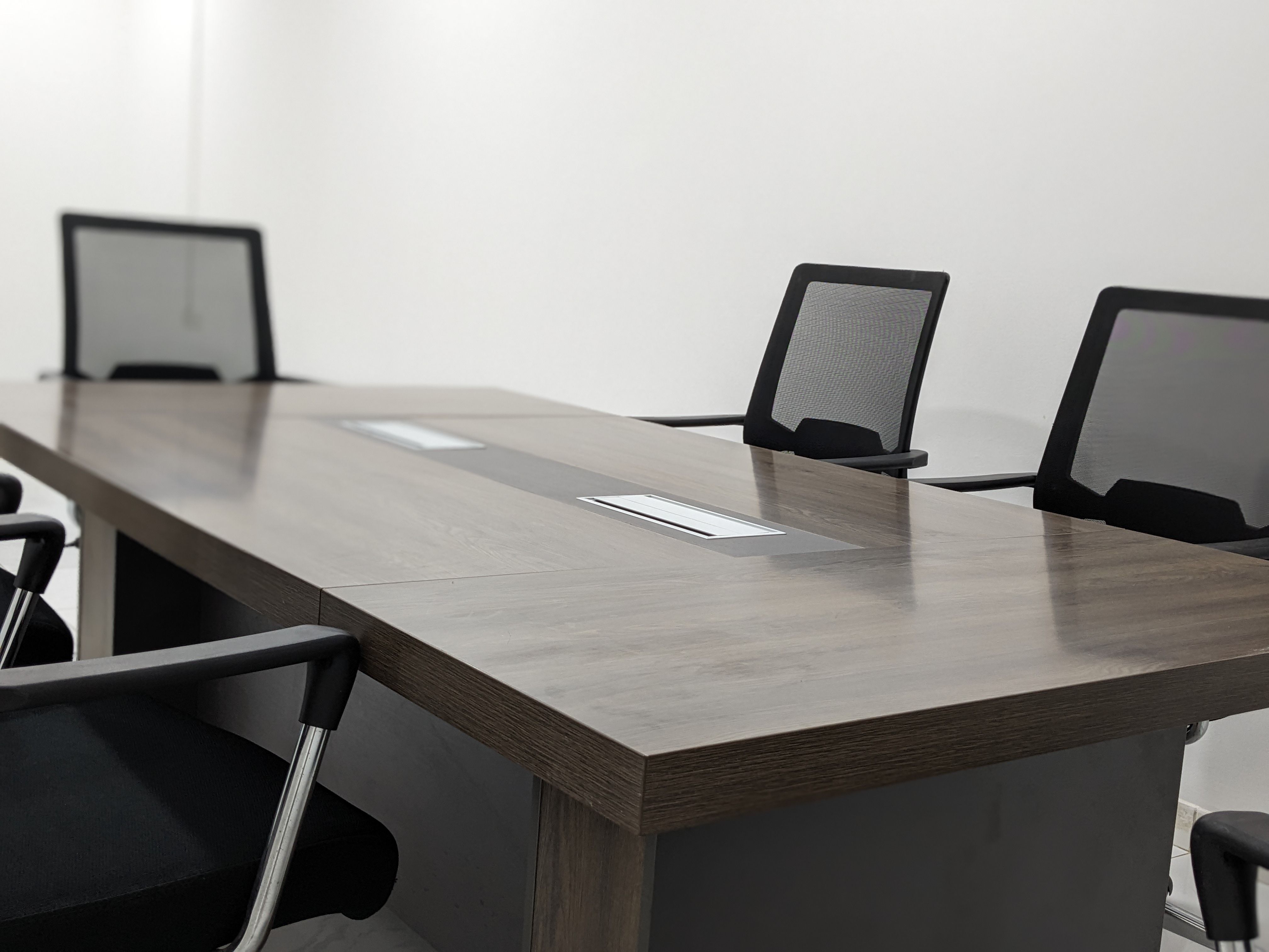 An empty conference room with a table and black office chairs.