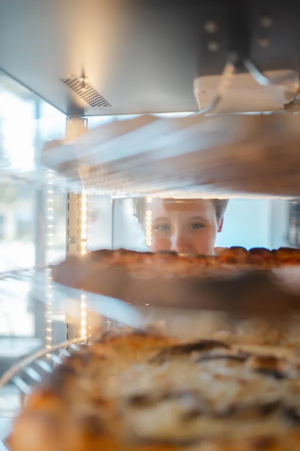 Kid looking at fresh pizza slices in the warming cabinet at Pizzeria Mungo — New York style pizza by the slice for lunch or dinner for kids in Richmond VA.