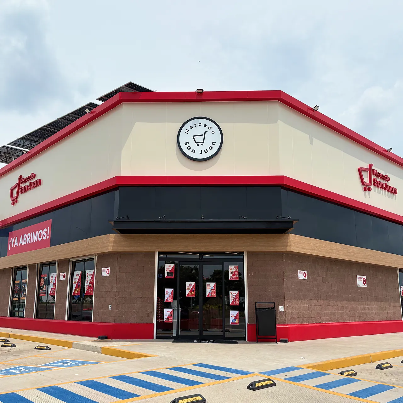 Fachada de Mercado San Juan con letrero rojo y blanco y marcada zona de accesibilidad en el estacionamiento.