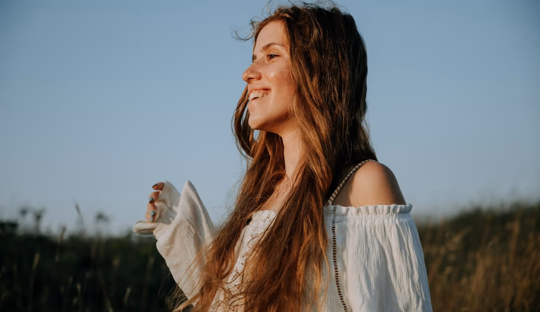 A woman with long hair standing in a field.