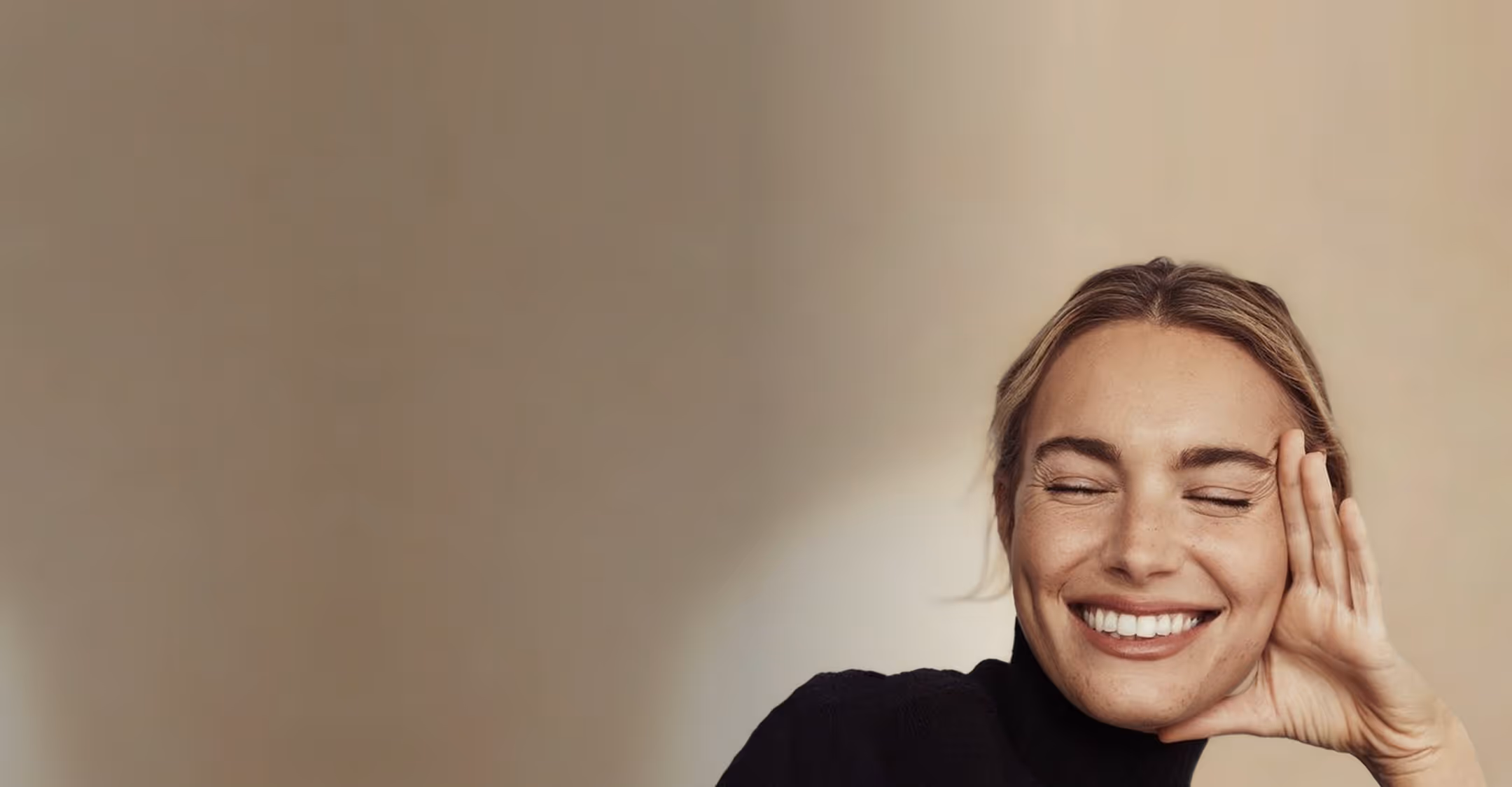 A woman smiling with her hands on her face.