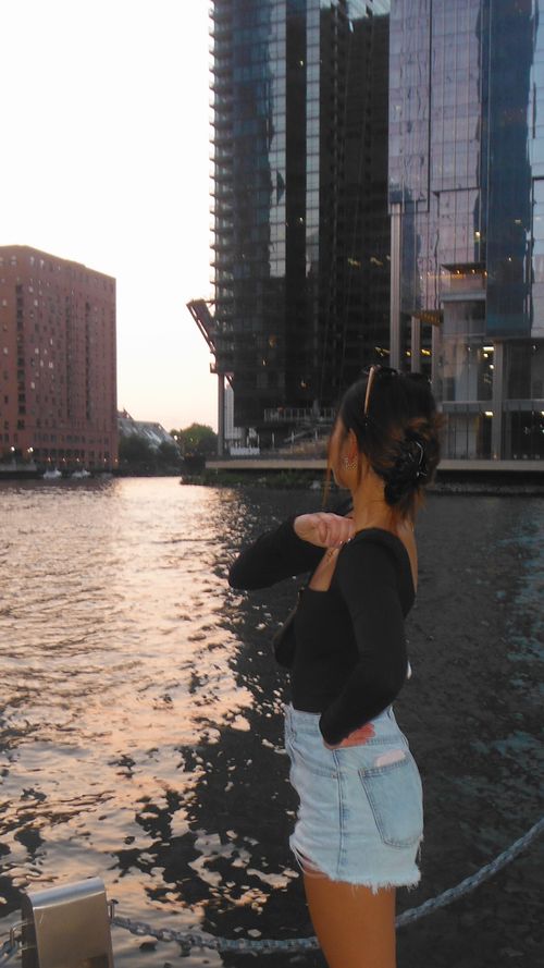 Janie's back turned facing the Chicago river at sunset.