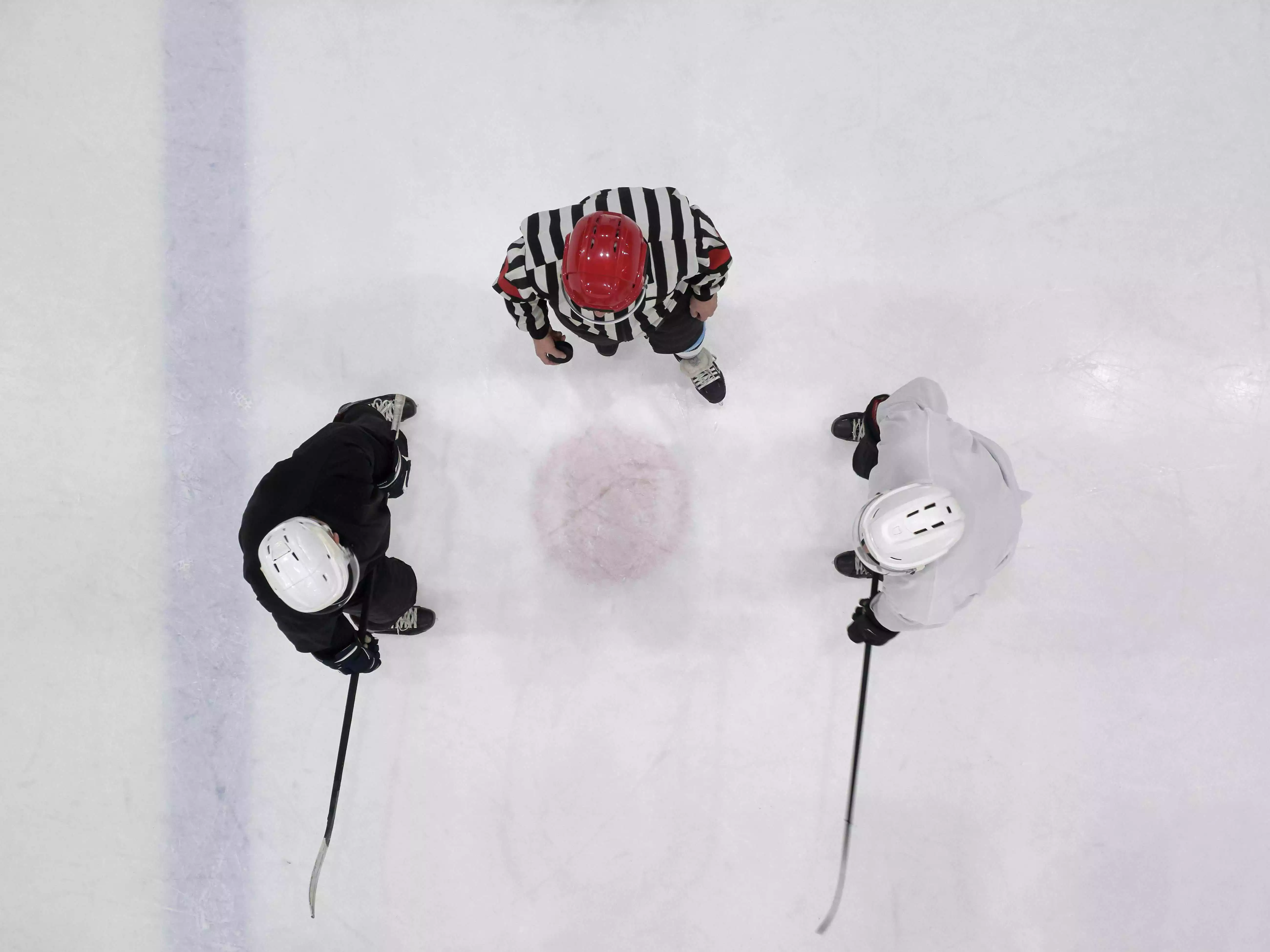 Two hockey players and a referee about to take a face-off.