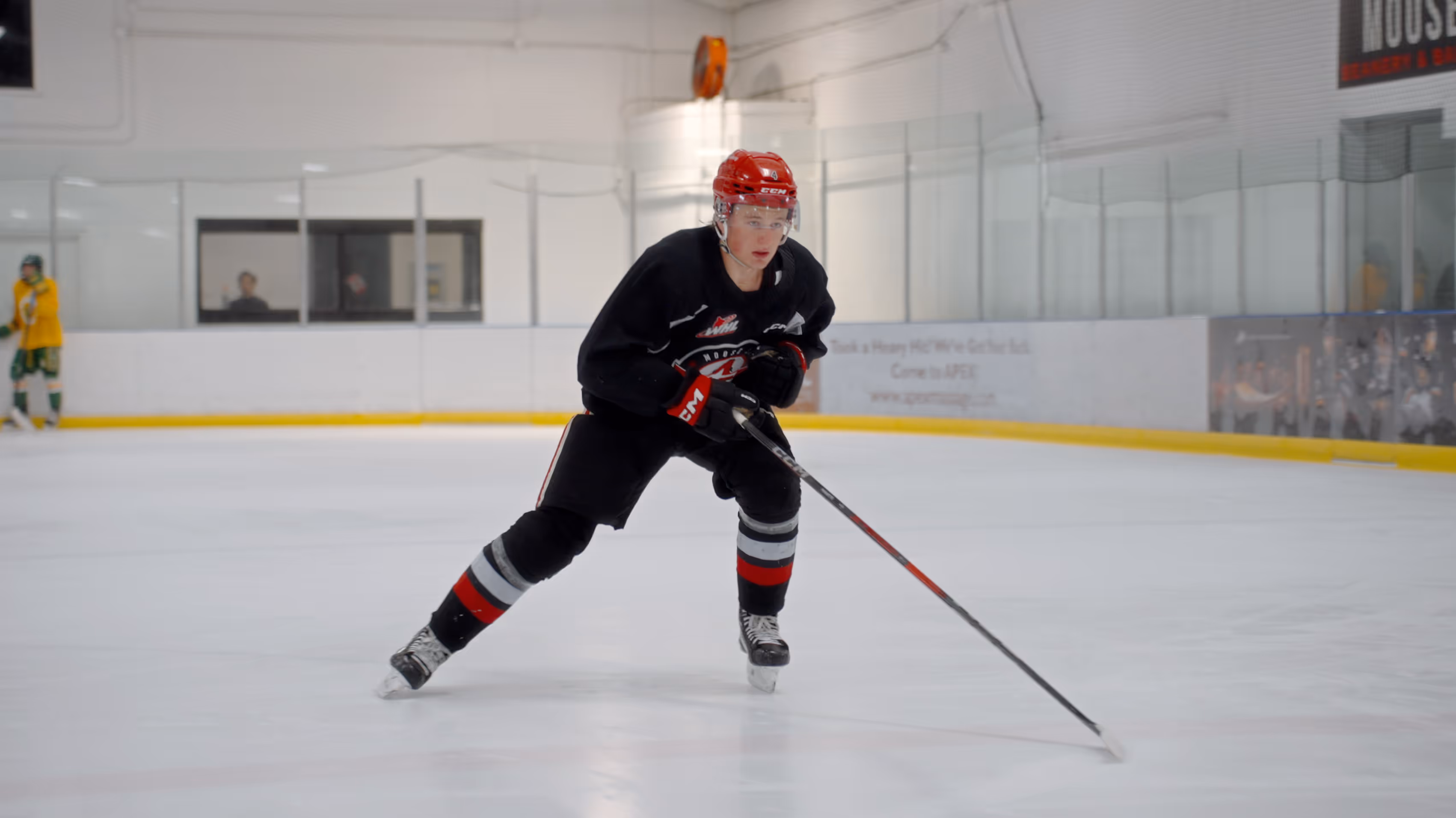 A hockey player being coached by Cole McBride on his skating technique.