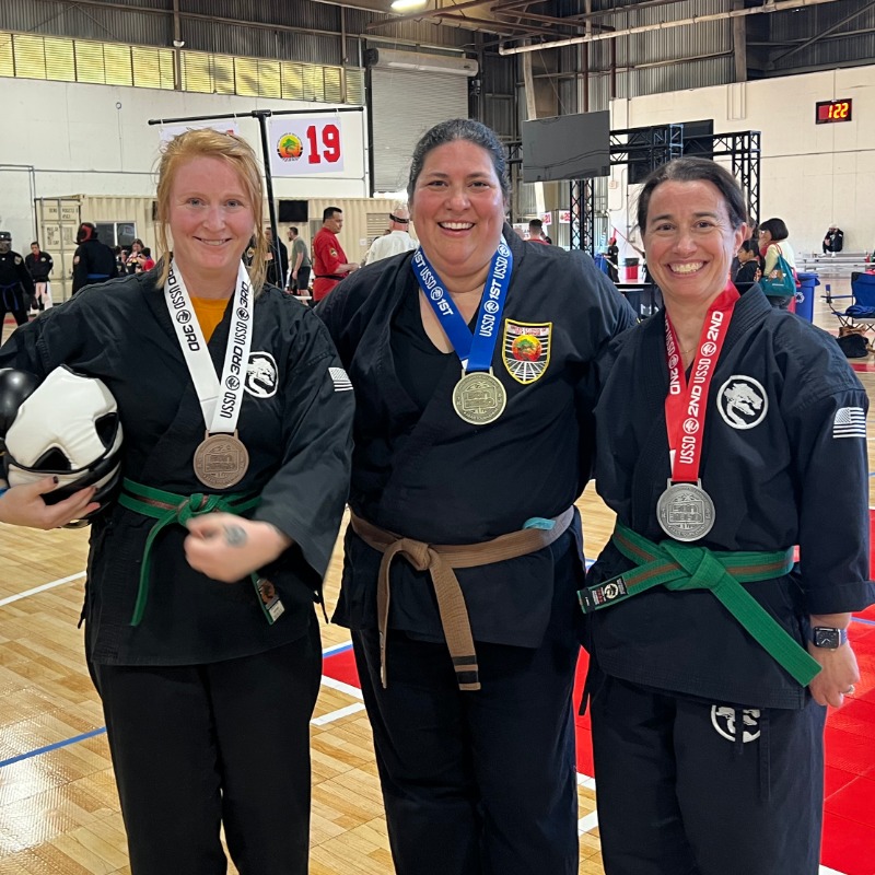 A group of Karate students posing together with their new rank certificates.