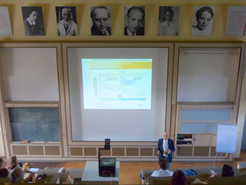 Lecture on headache treatment with presentation slides in a university auditorium.