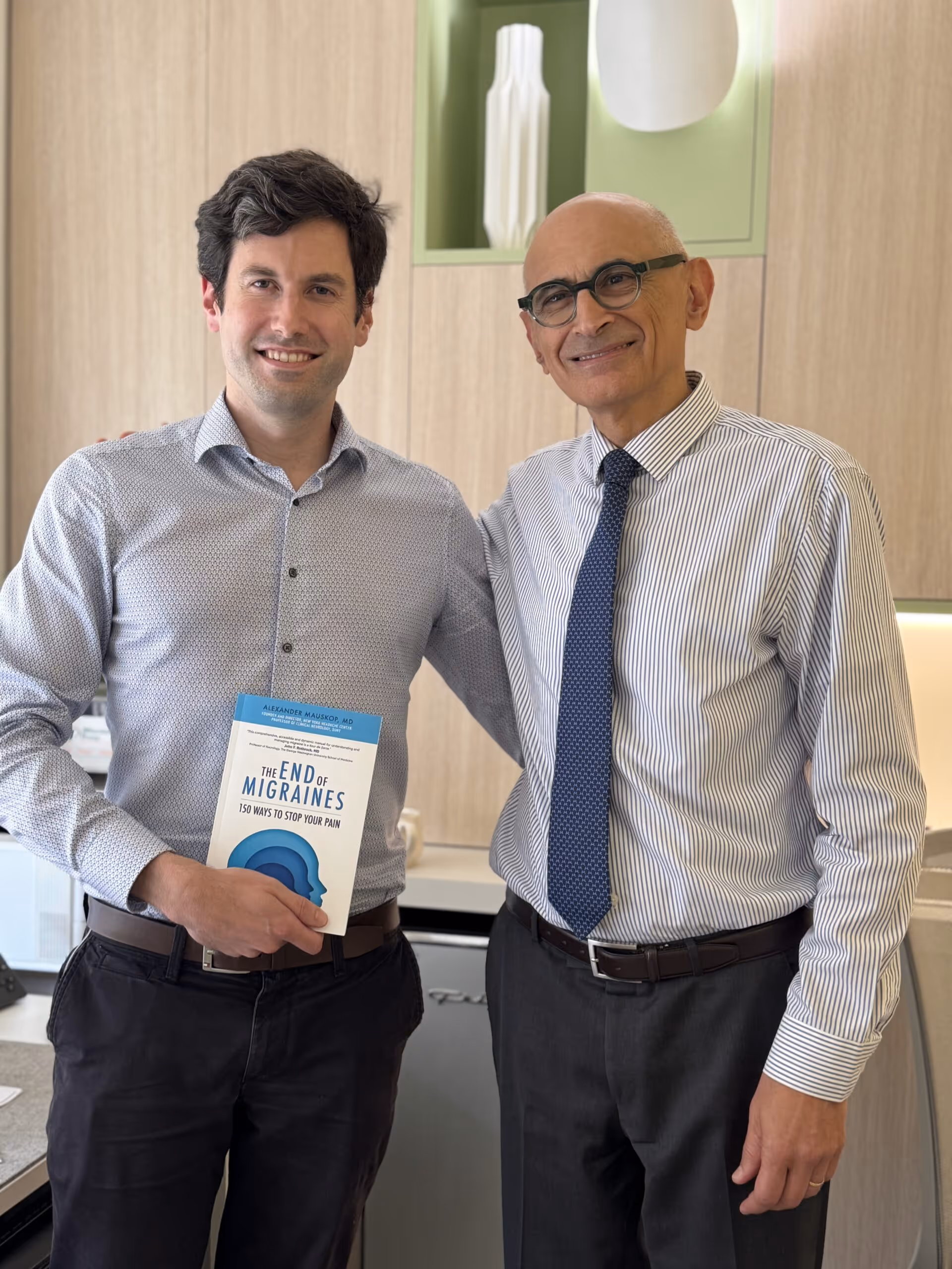 Two doctors at the New York Headache Center, one holding the book “The End of Migraines.”