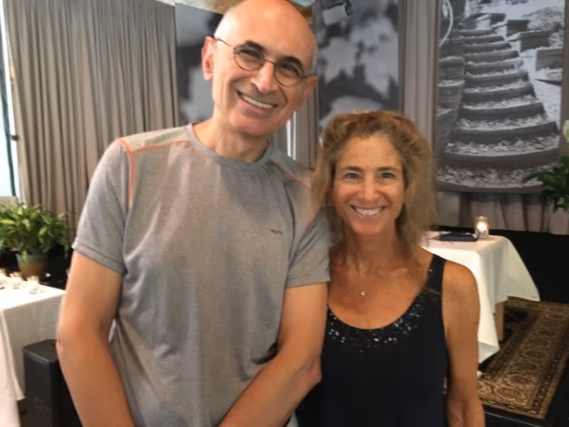Smiling man in casual sportswear standing next to a woman in a sleeveless top, both posing for the camera.