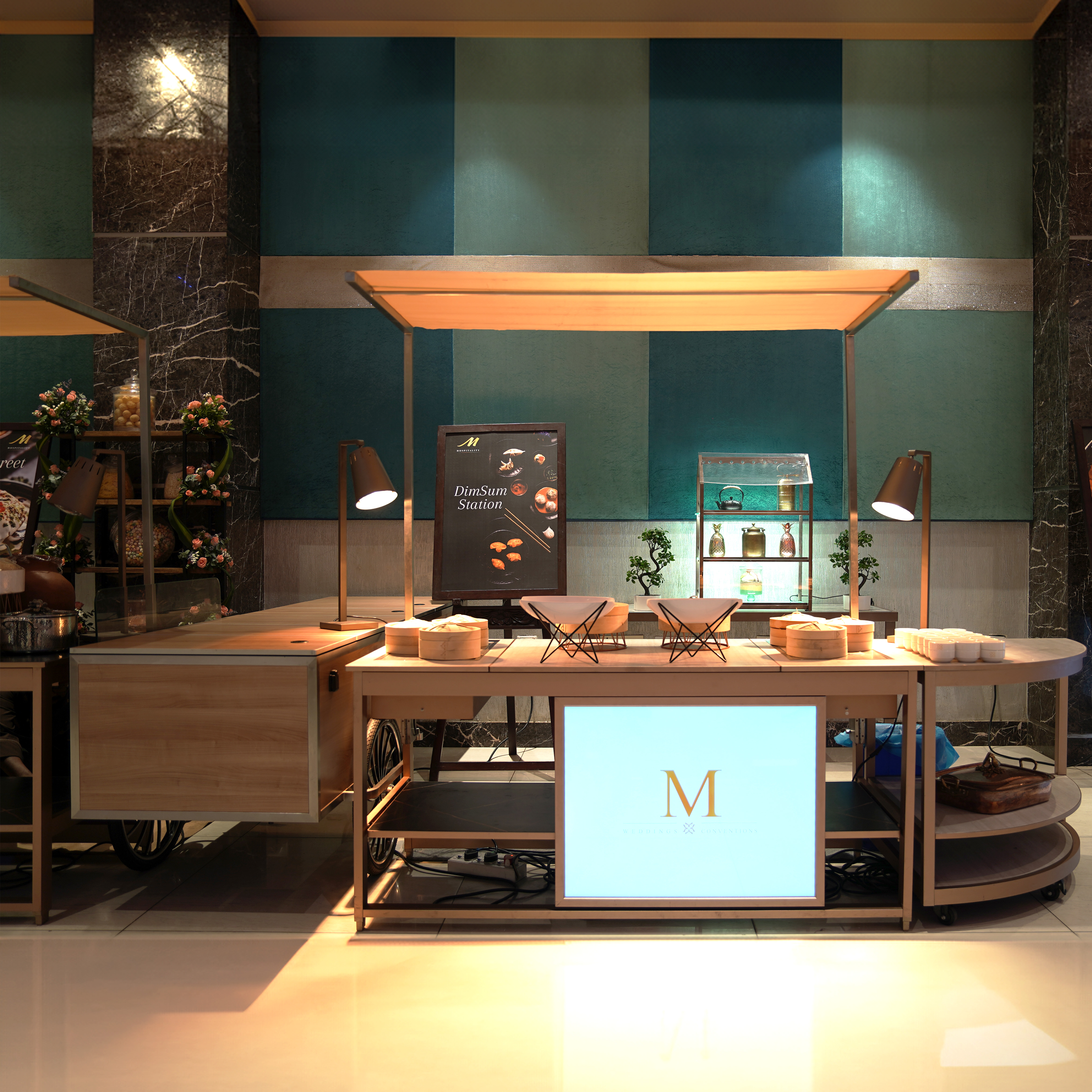 Dim sum station cart with bamboo steamers, plates, and tea cups under warm lights in a restaurant setting.