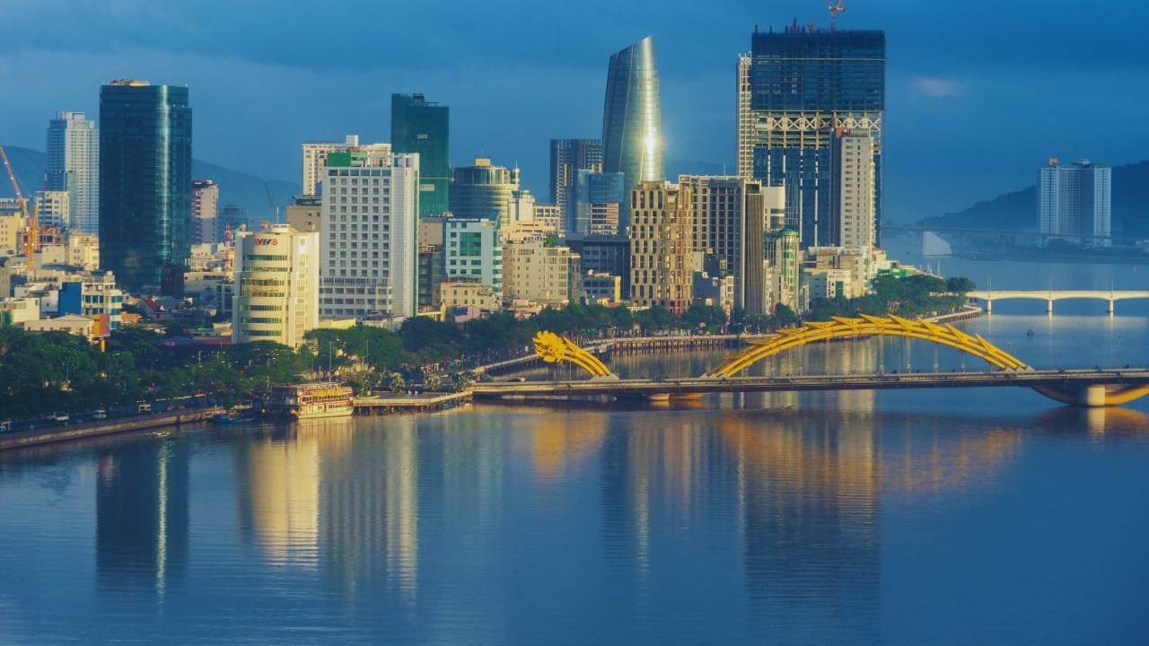 The golden Dragon Bridge spans the Han River in Da Nang at dusk.