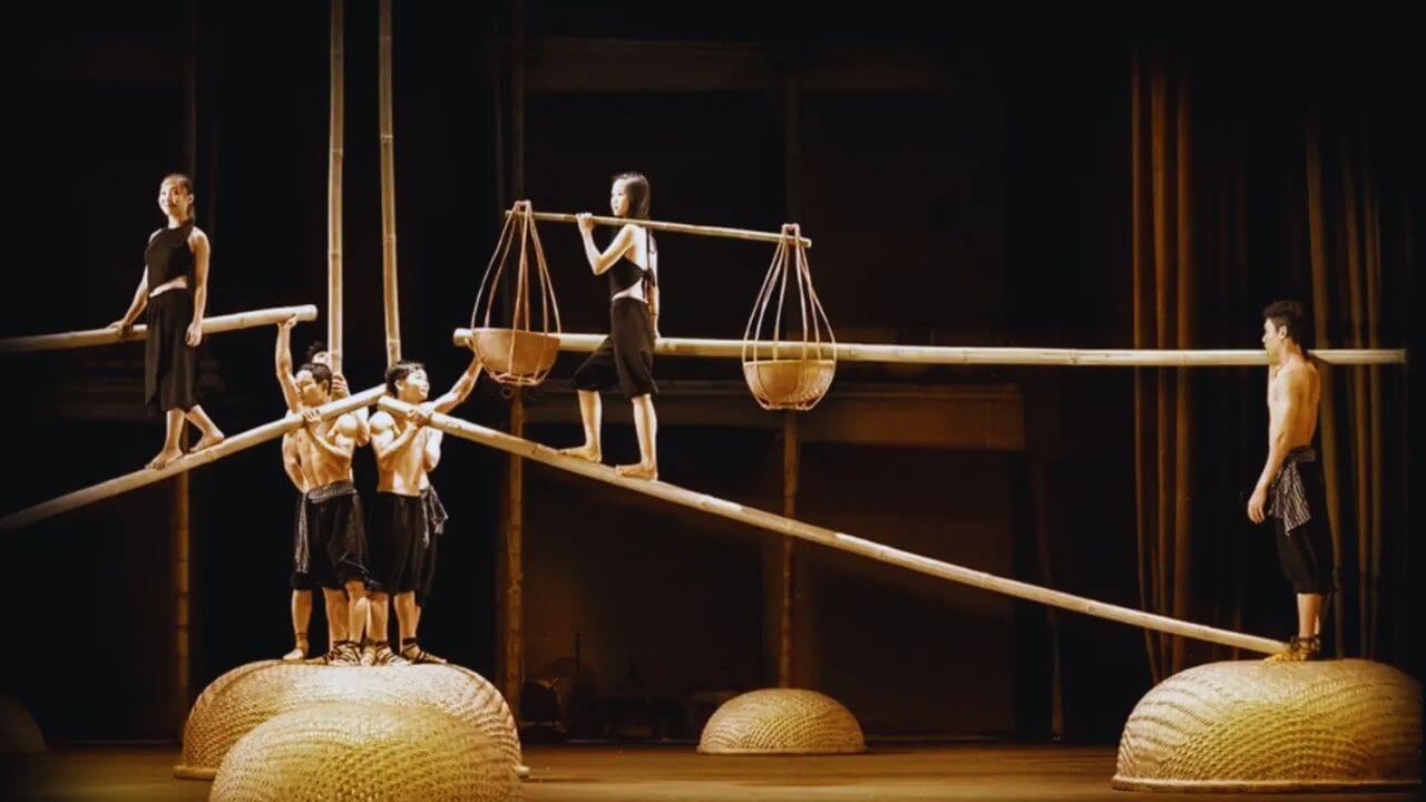 A O Show performers balance on bamboo poles in a dramatic cultural performance in Saigon.