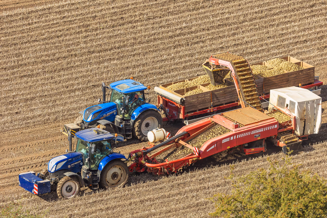 Three large metallic grain silos with connecting structures under a cloudy sky.