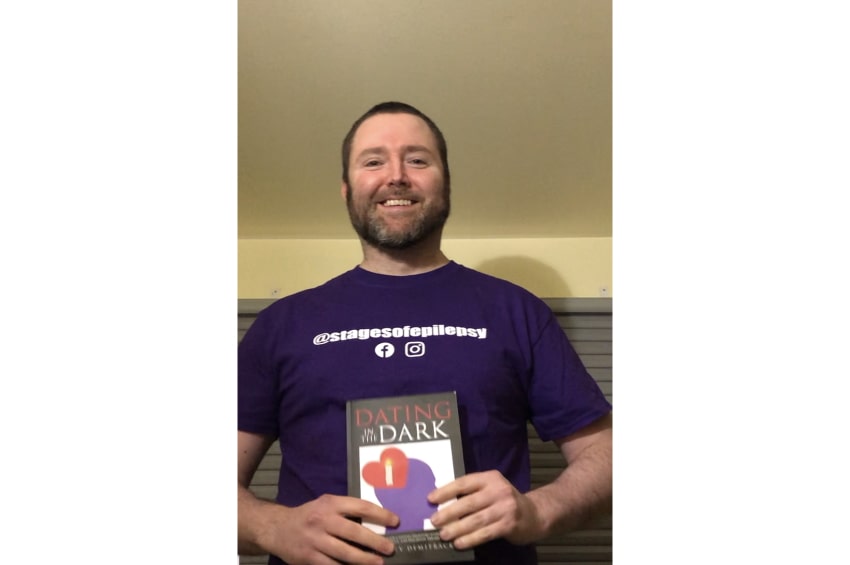 Jeff tenant son livre sur son parcours avec l’épilepsie, souriant à la caméra.