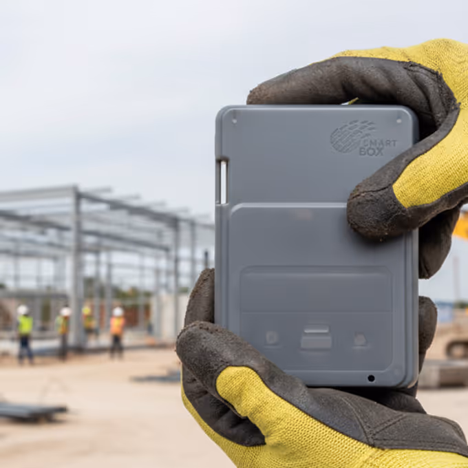 Man holding SmartBox with view of construction site in background