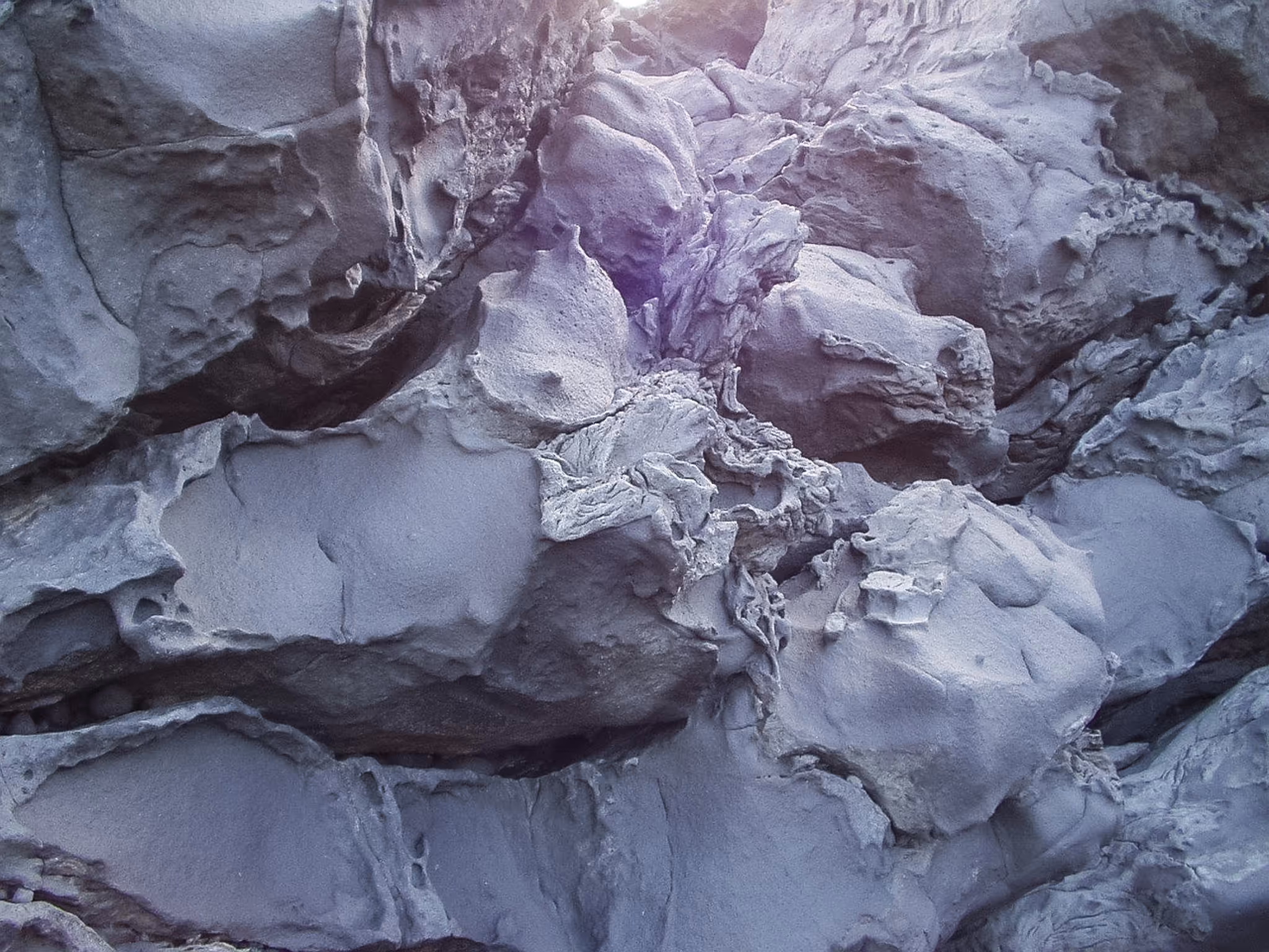 Close-up view of textured, irregular gray rock formations with rough surfaces.