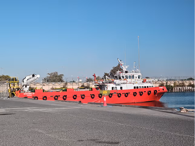 A red boat is docked at a pier.
