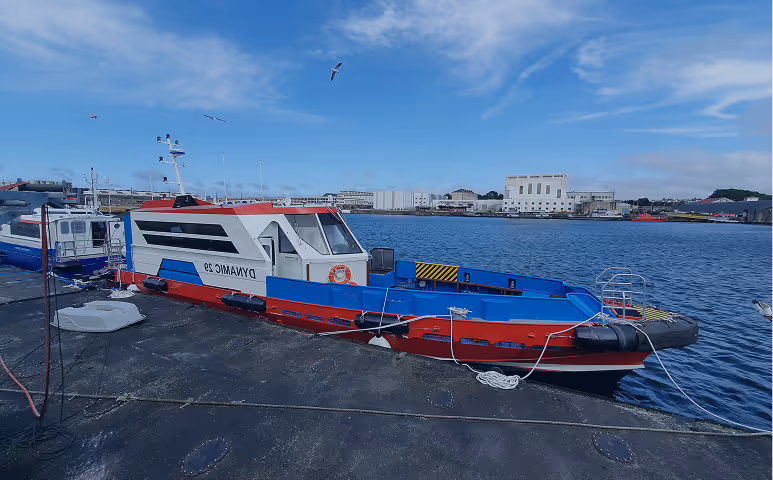 A blue and red boat is docked at a pier.
