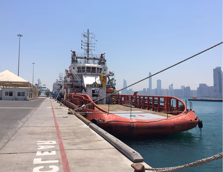 A large red boat is docked at a pier.