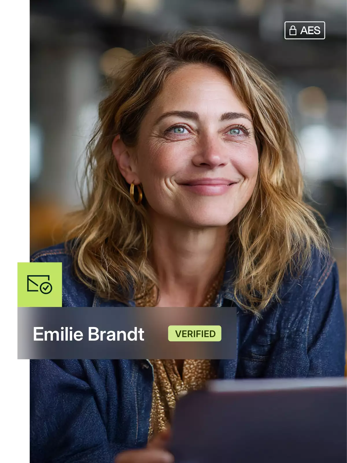 Woman with blue eyes and blond, wavy hair is smiling, wearing gold earrings and a blue jacket.