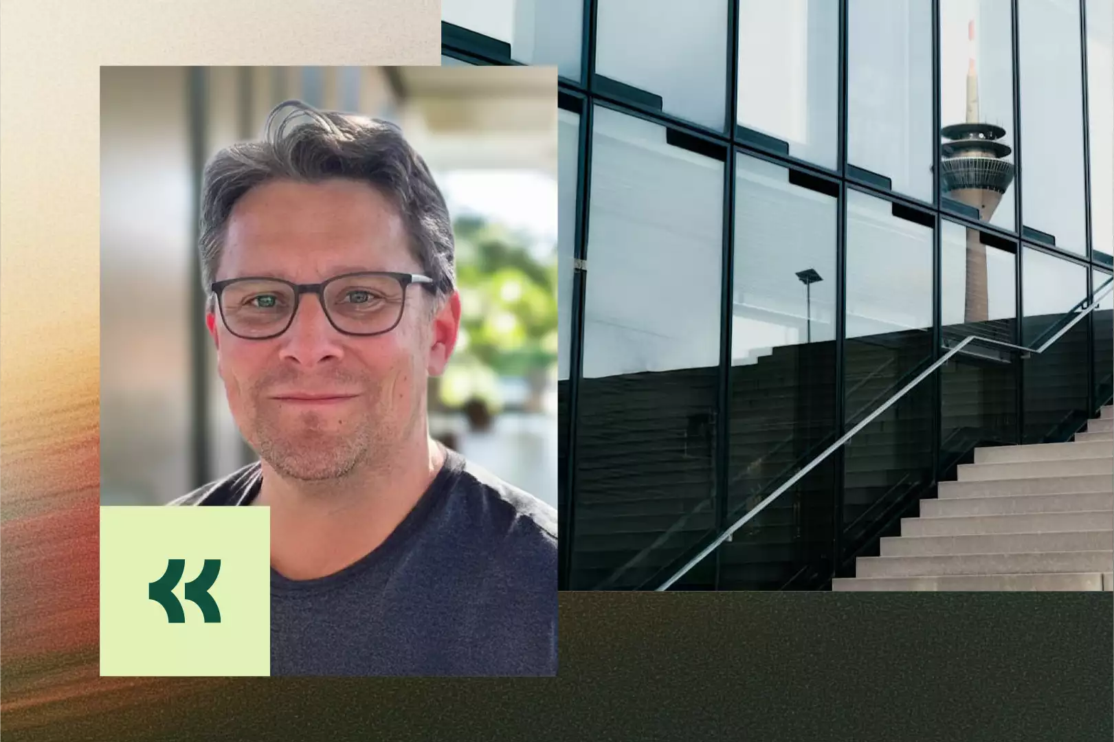 Mann mit Brille und braunem Pullover spricht vor verschwommenem Hintergrund, neben einer hellen Wohnhausfassade mit Bäumen und Kopfsteinpflaster.