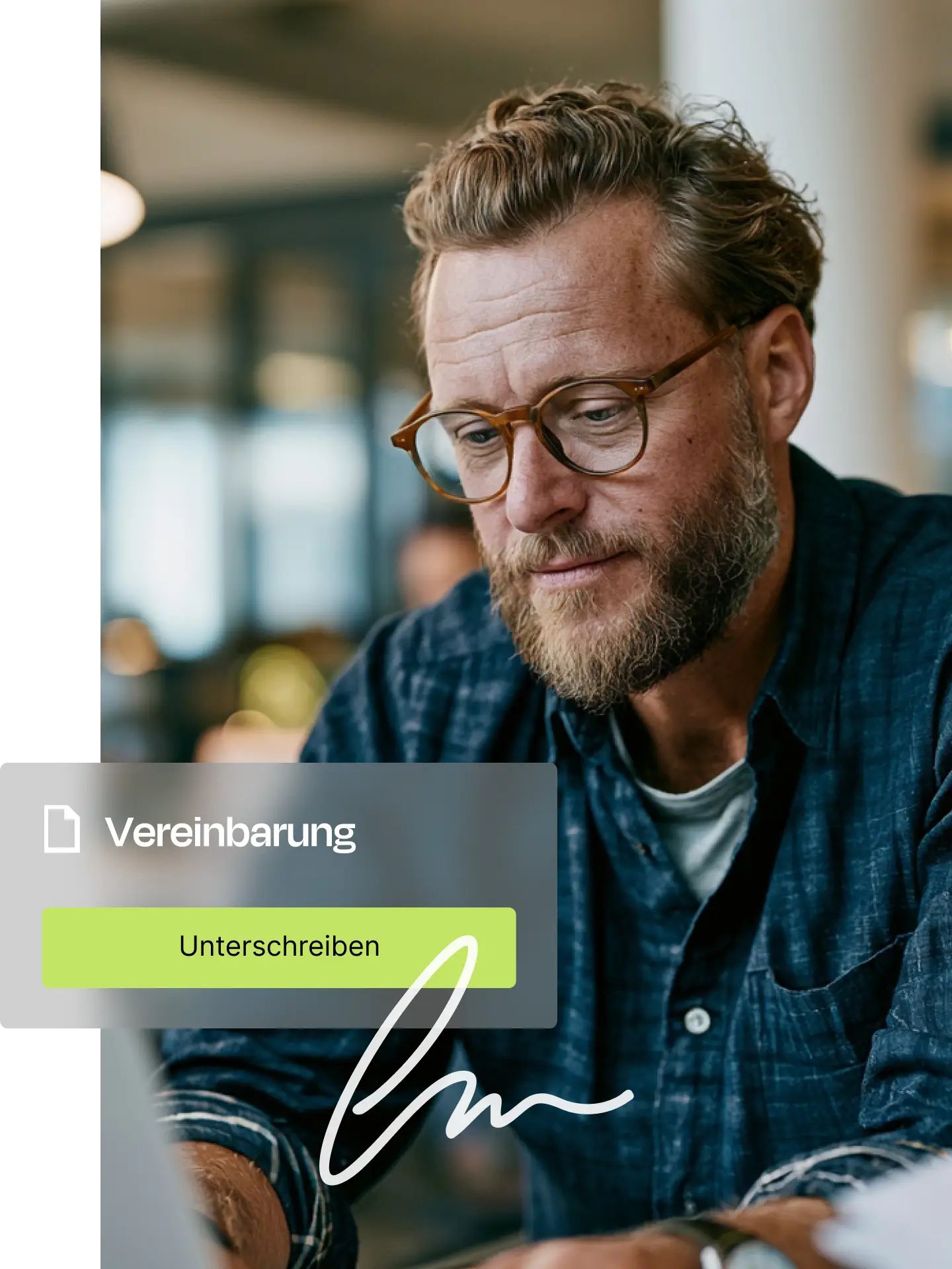 Mann mit Brille und Bart konzentriert beim Unterschreiben einer Vereinbarung am Laptop