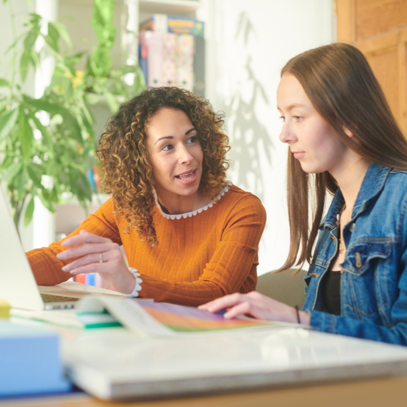 Advisor guiding a student through interview preparation on a laptop