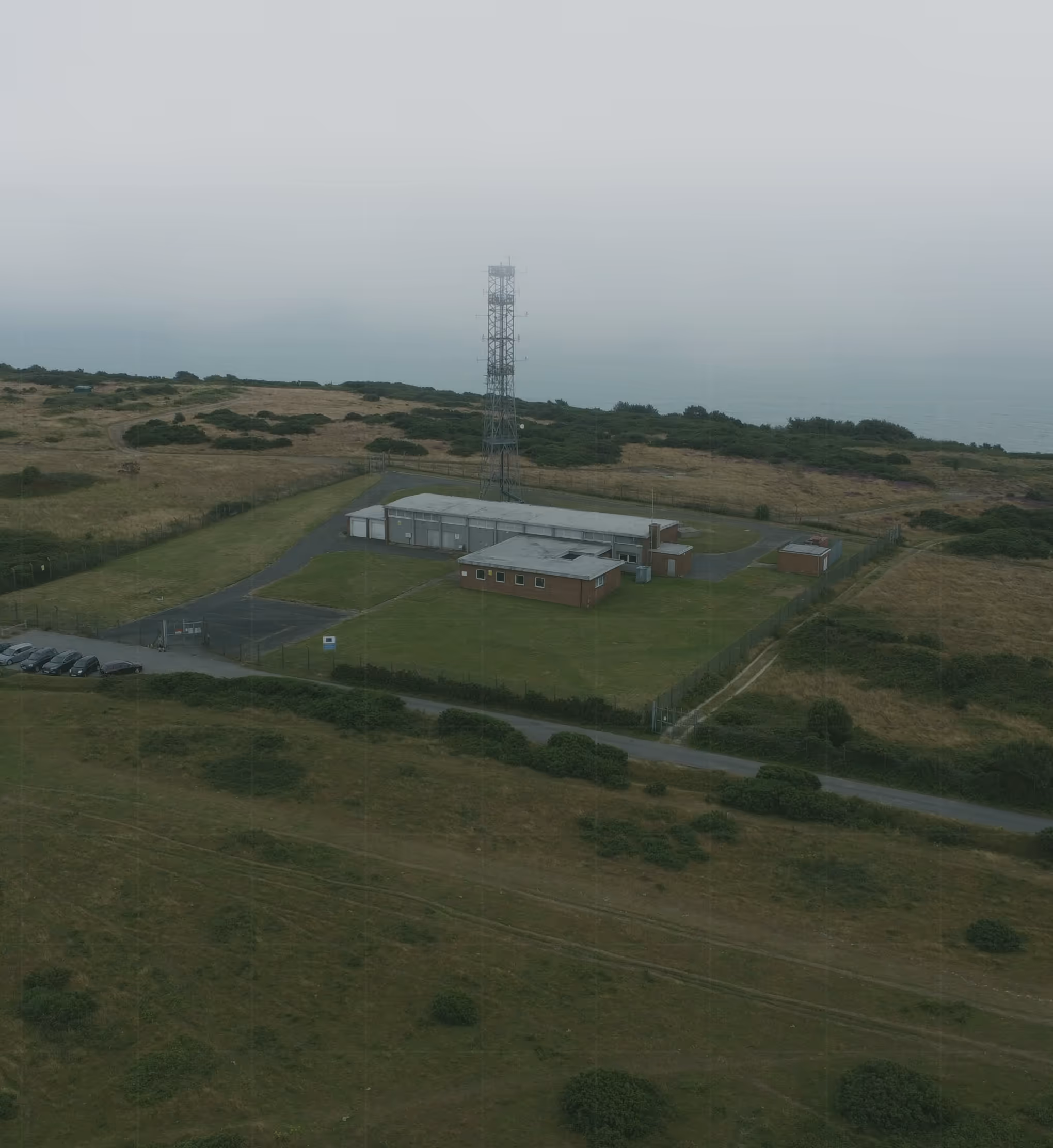 Remote coastal communication tower and facility captured by drone, demonstrating advanced AI-assisted sensor inspections for multi-domain data collection in critical infrastructure monitoring.