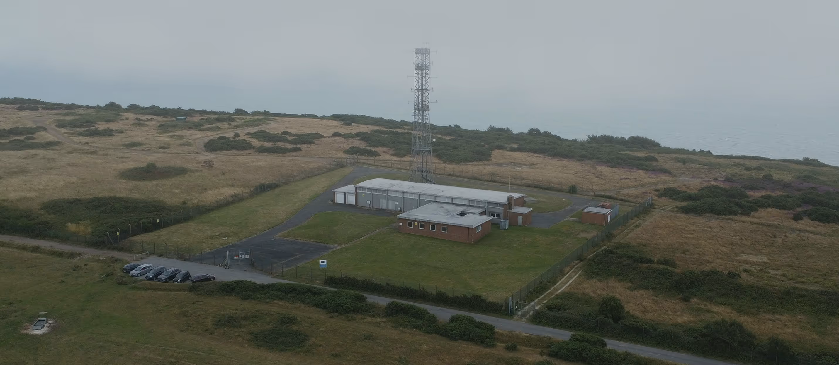 Aerial view of a secured coastal communications facility with a tall antenna tower, representing Testudo’s end-to-end solutions for collecting multi-domain data and delivering actionable intelligence for critical infrastructure monitoring with full regulatory compliance.